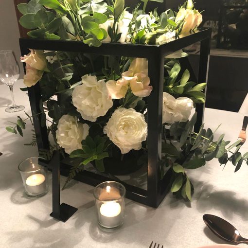 black metal cube with floral arrangement within