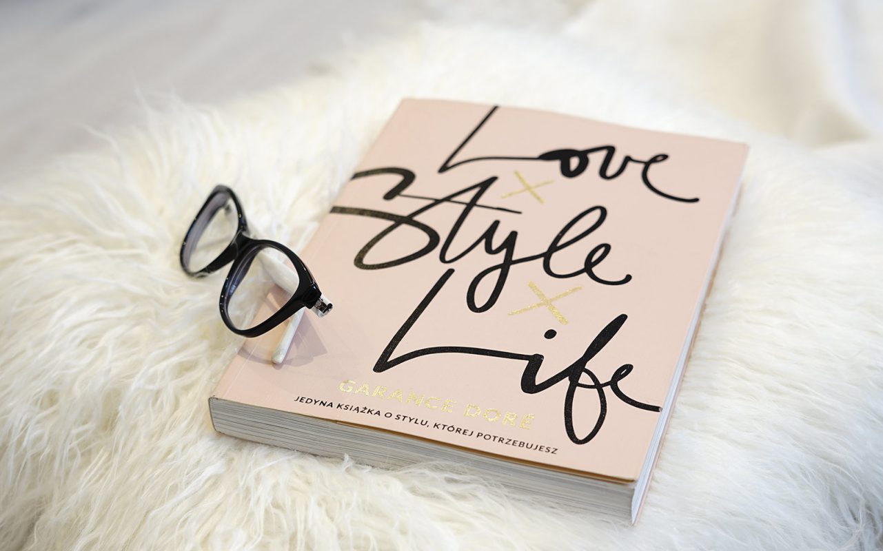 Book with title love style life on white rug with glasses