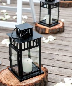 Black lanterns with candles sitting on wooden tree slices