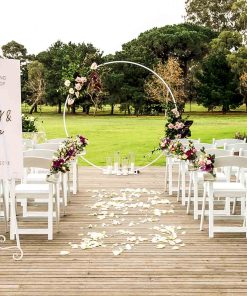 Contemporary wedding ceremony setting showing chairs, white circular arch with floral arrangements and signage