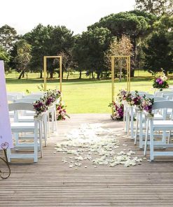 Glam outside wedding setting showing chairs, metal stands with floral arrangements and signage