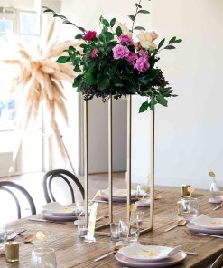 Gold metal stand with floral arrangement on table