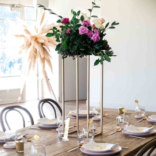 Gold metal stand with floral arrangement on table