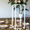 White metal stand centerpieces on table with floral arrangement