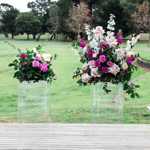 Clear acrylic plinth stands with floral arrangements