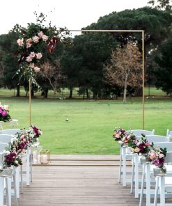 Gold ceremony wedding arch with floral arrangement