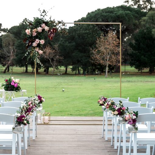 Gold ceremony wedding arch with floral arrangement