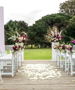 Modern outside wedding setting showing chairs, plinths with floral arrangements and signage