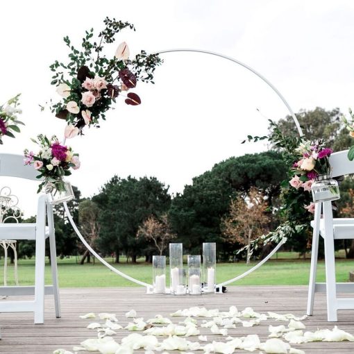 White Circular Wedding Arch with flowers on deck with candles and rose petals