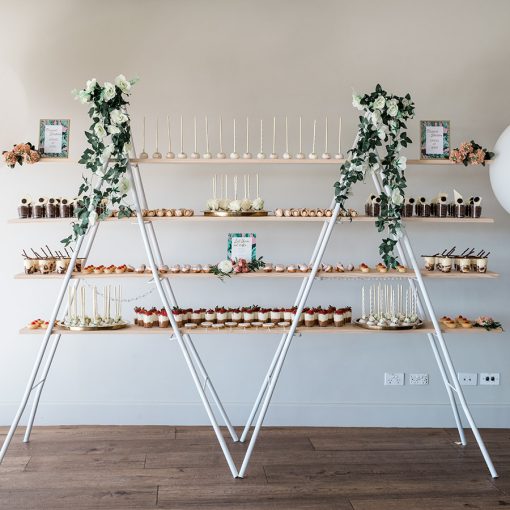 4 tier trestle style shelf adorned with numerous dessert offerings