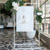 White metal stand frame with welcome signage for Anthony and Natalie's wedding adorned with flowers