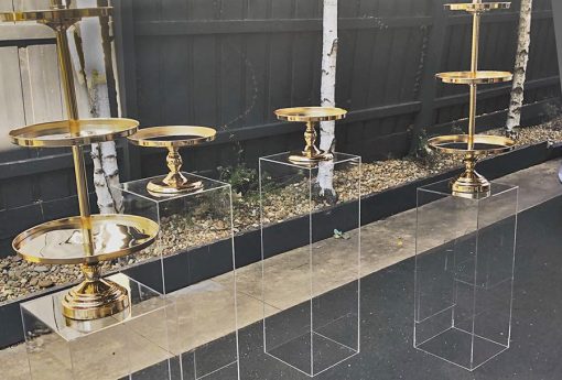 Clear plinths with gold single and triple cake stands on top