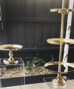 Two gold cake stands on top of clear plinths