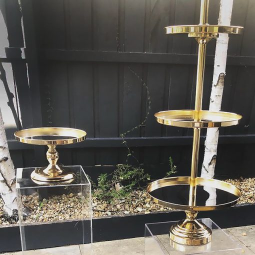 Two gold cake stands on top of clear plinths