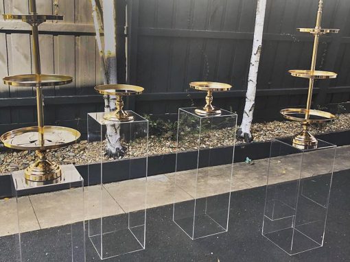 4 clear plinths with 4 gold cake stands atop