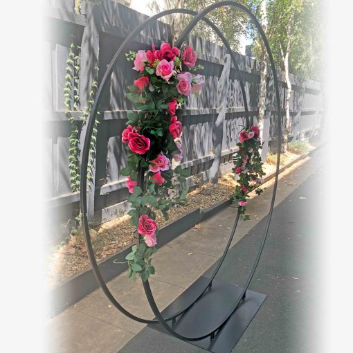 Metal double circular arch with pink flowers standing in driveway