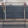 Black metal frame with flowers 2.3m square with mesh screen in middle standing in driveway