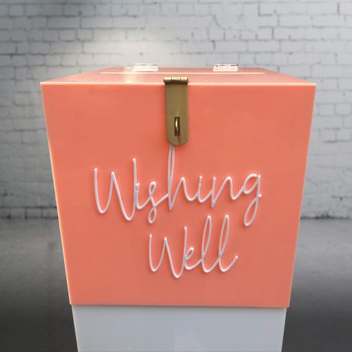 Front view of 300mm square blush pink acrylic wishing well box with white ‘wishing well’ acrylic script text on front and lock sitting on white plinth.