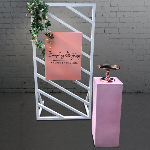 Blush pink plinth and cake stand in front of two separate white window panel backdrops each 2m high by 1m wide. Each frame has 8 diagonal slats.