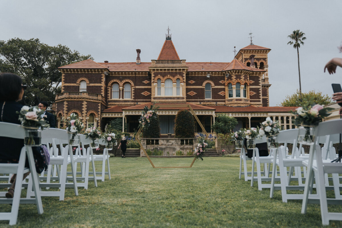 Garden wedding ceremony setup with white chairs and floral arch Melbourne
